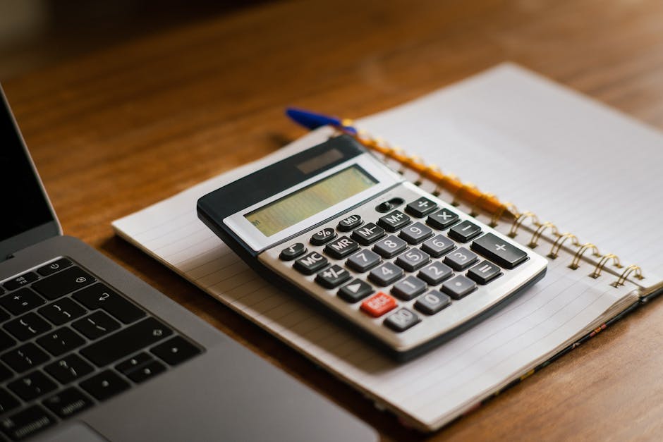 Calculator and laptop on a desk for planning $1,000 loan repayment in Canada