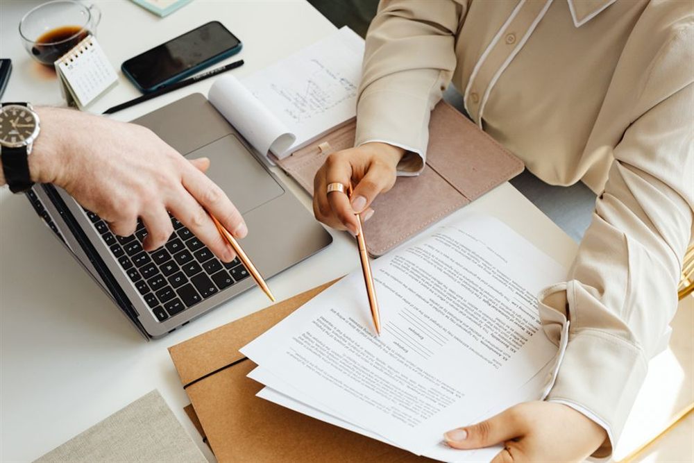 Two people comparing loan options and documents with a laptop before borrowing $1,000 online in Canada