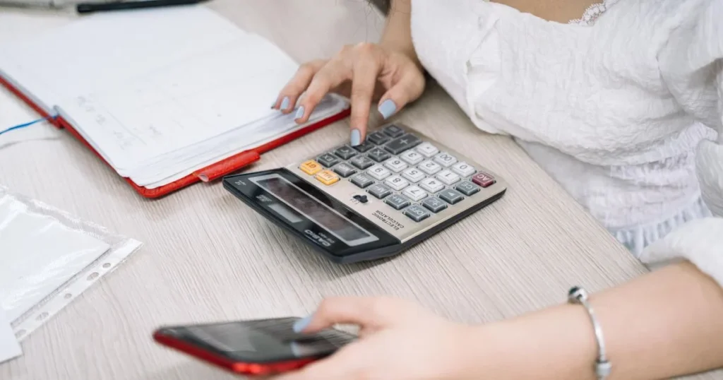 Woman with a calculator and smartphone planning to borrow $200 online in Canada