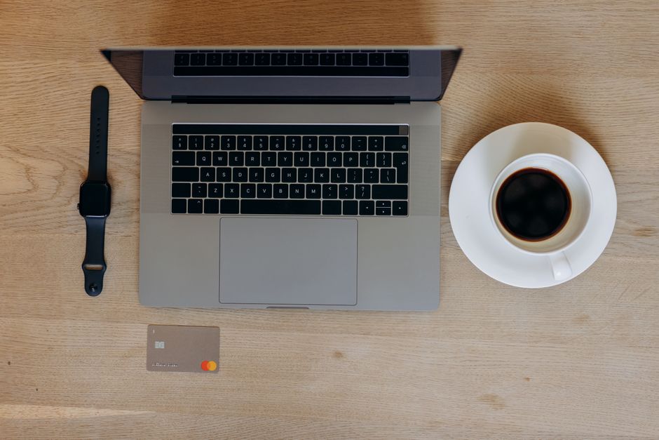 Laptop, card, and coffee on a desk for online banking when borrowing $200 in Canada