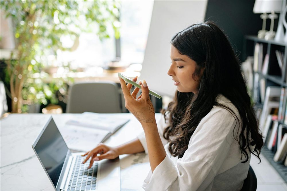 Woman completing an online loan application on her phone and laptop to borrow $200 online in Canada