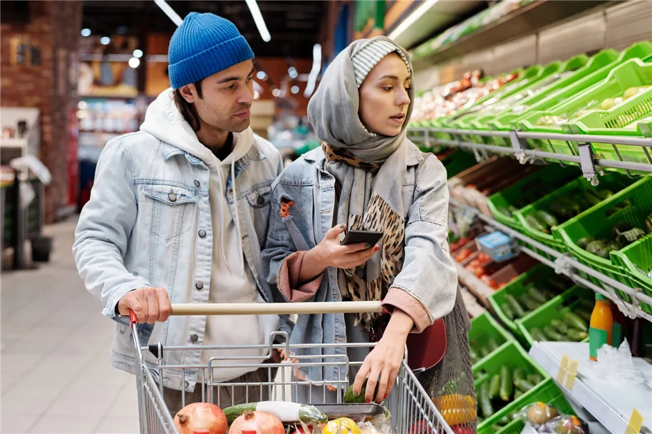 Couple comparing grocery prices on a phone while shopping on a budget in Canada