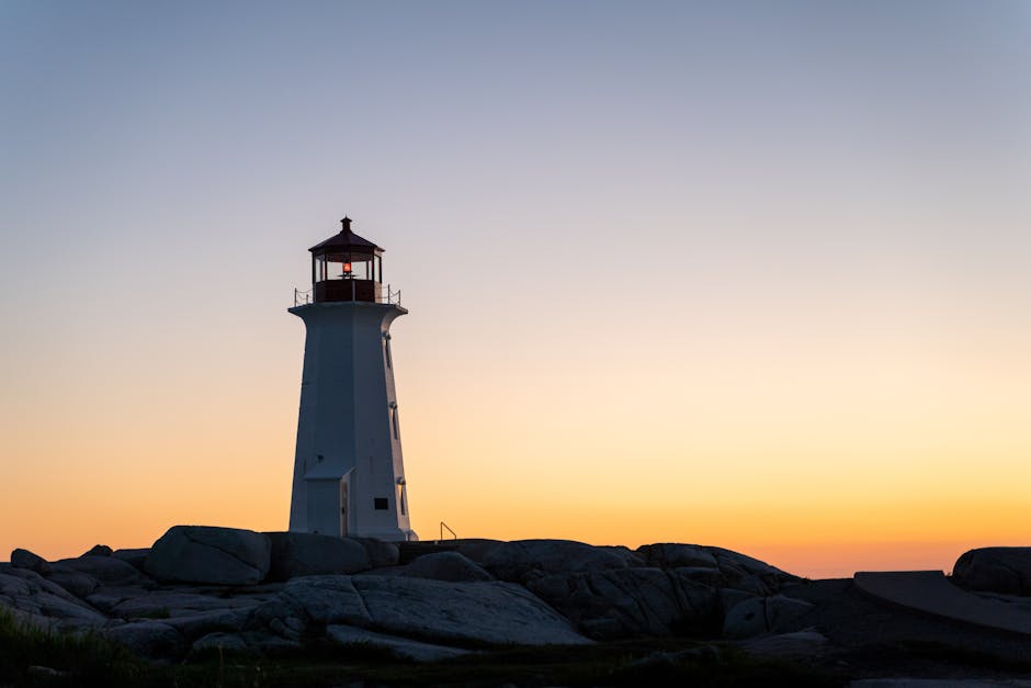 Peggy's Cove lighthouse silhouetted against a vivid sunset sky in Nova Scotia, Canada