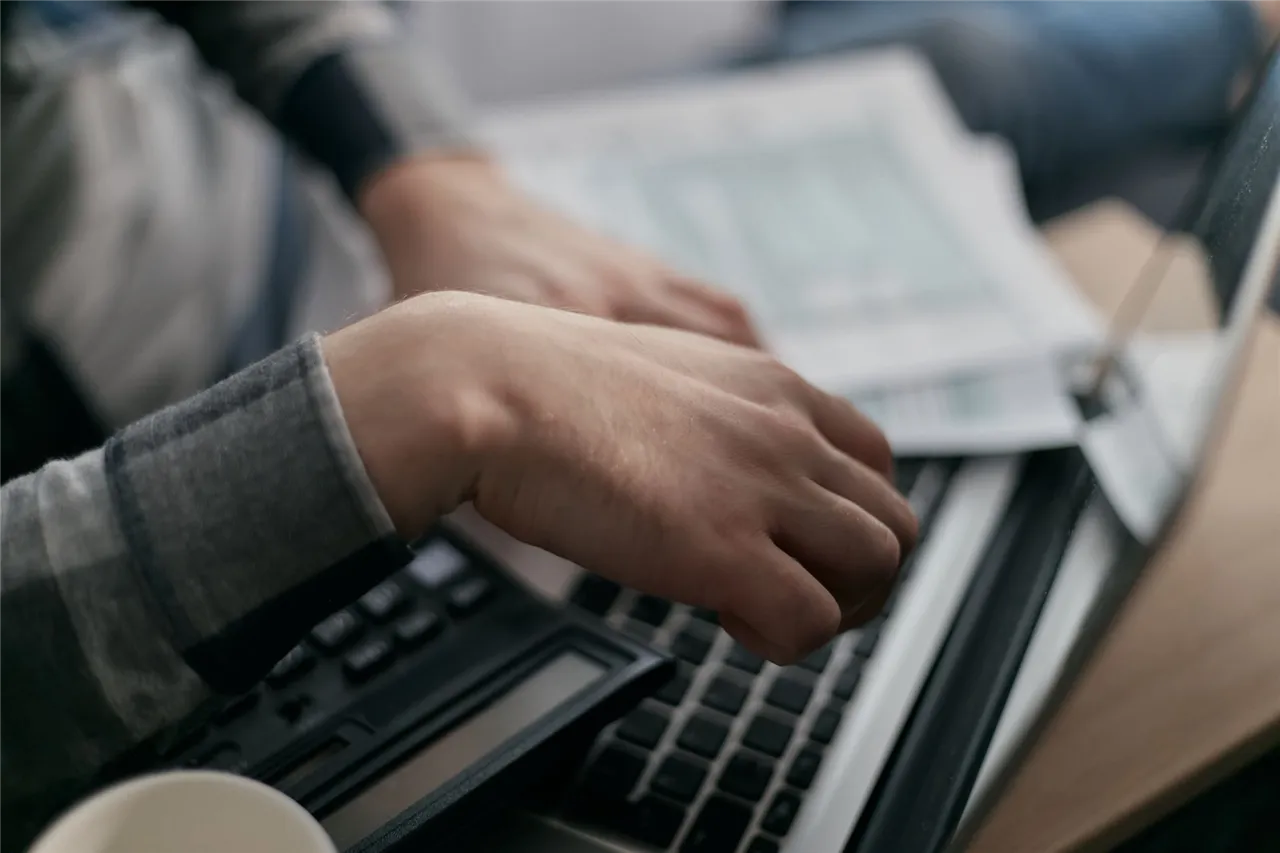 Calculating the cost to borrow money for bills with a calculator and laptop