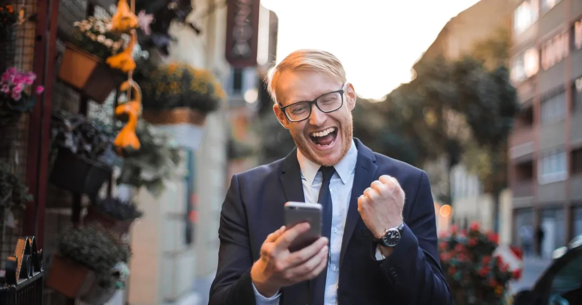 Canadian borrower celebrating a loan arriving by e-Transfer on his phone - borrow money right now