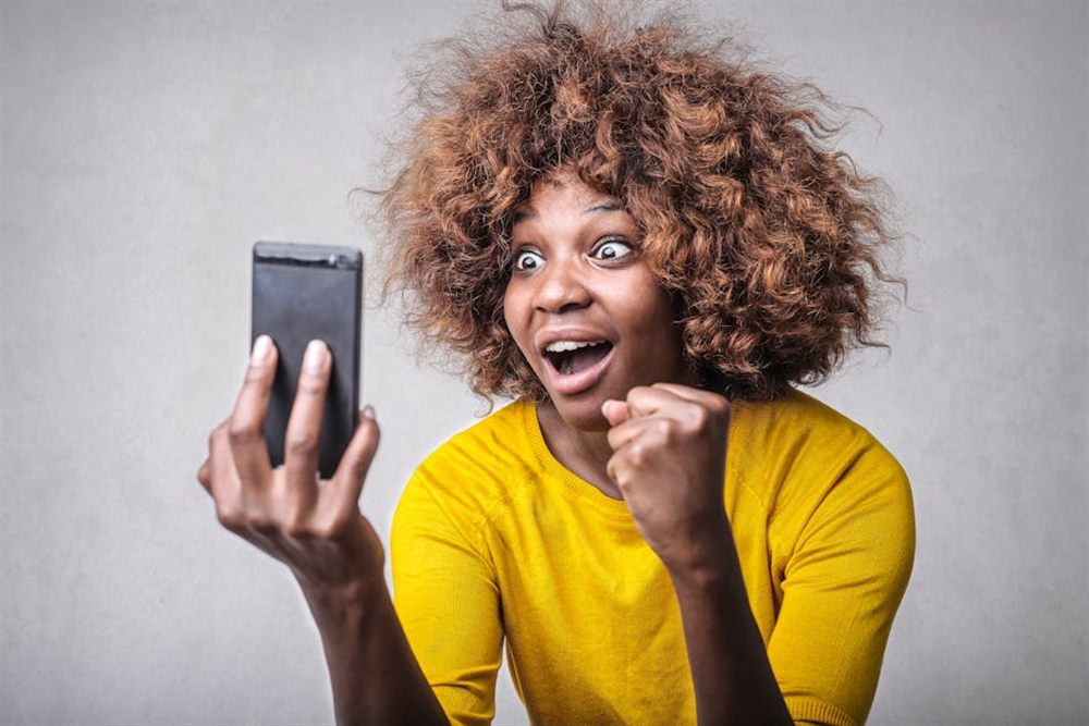 Woman excited at an Interac e-Transfer notification on her phone after borrowing money online in Canada