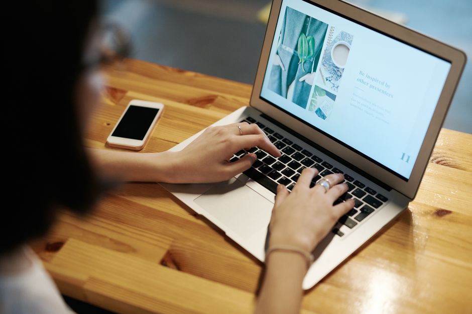 Person typing on a laptop with smartphone nearby to borrow money online in Canada