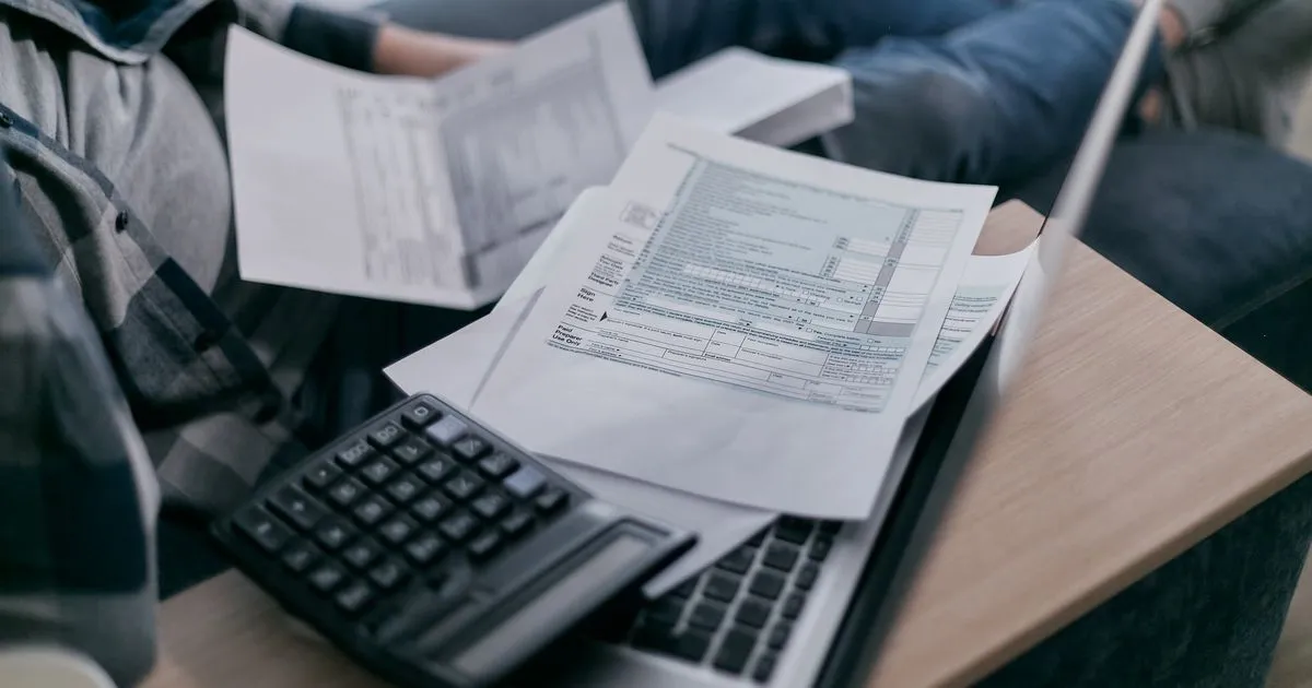 Person managing finances with a calculator and laptop when they need money now in Canada