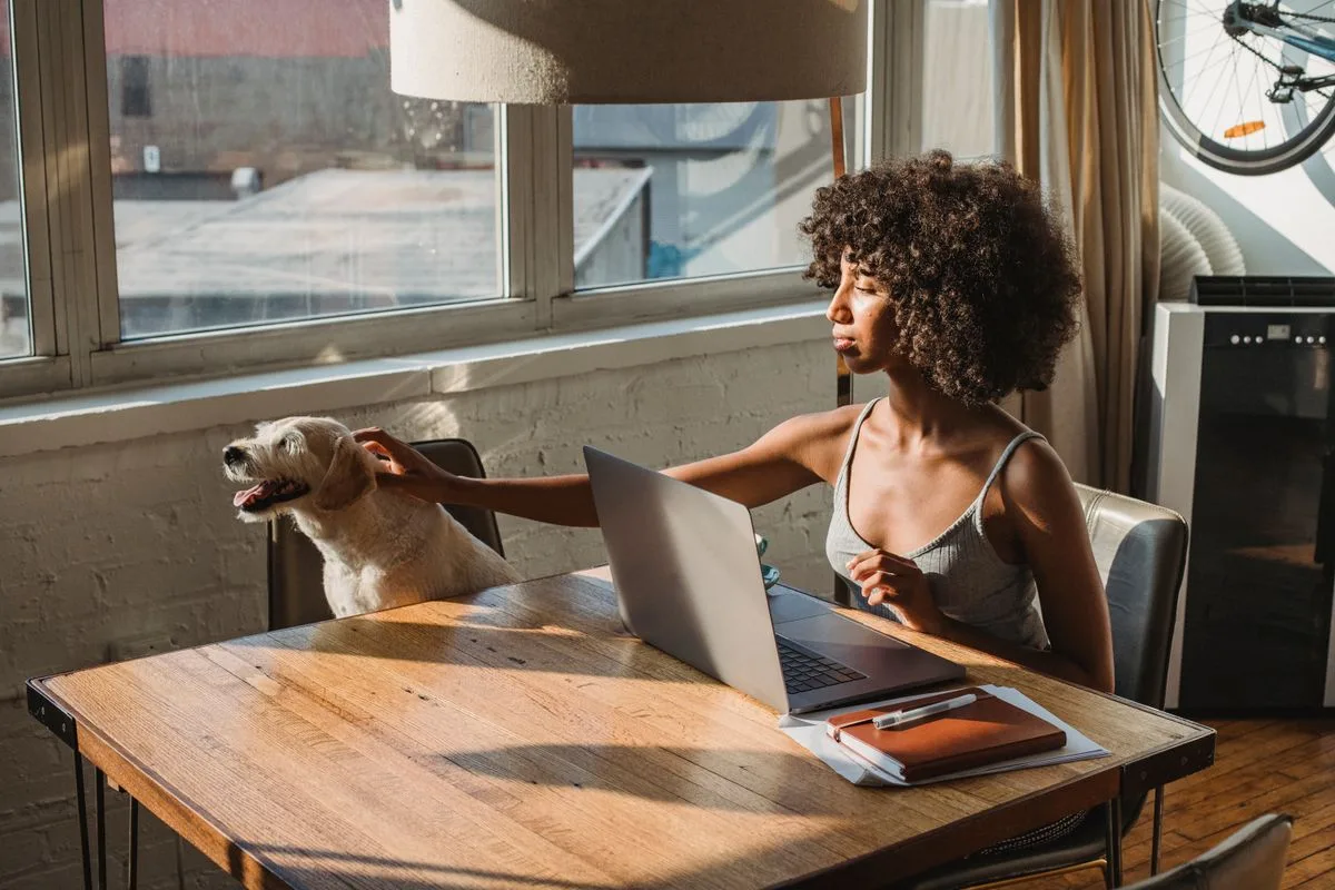 Pet owner applying online for a small vet bill loan from home with her dog beside her