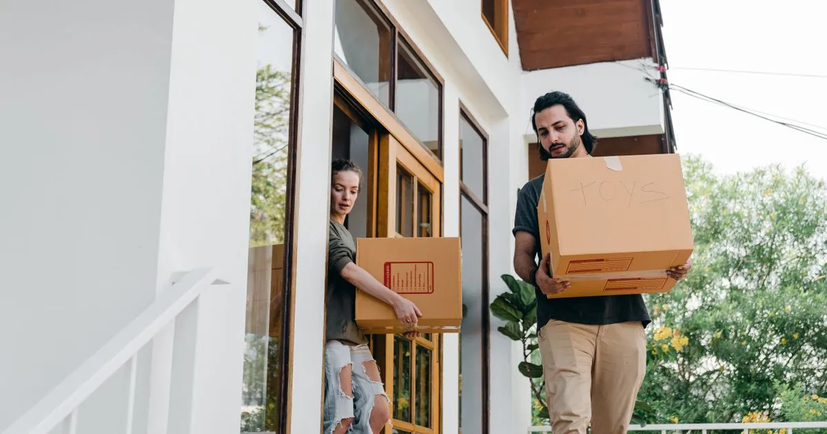 Couple carrying boxes on moving day - borrow $1500 online to cover the moving month