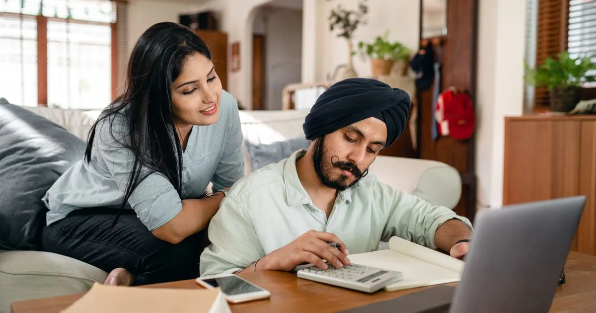 Couple planning installment loans Canada repayments at home with a calculator and laptop