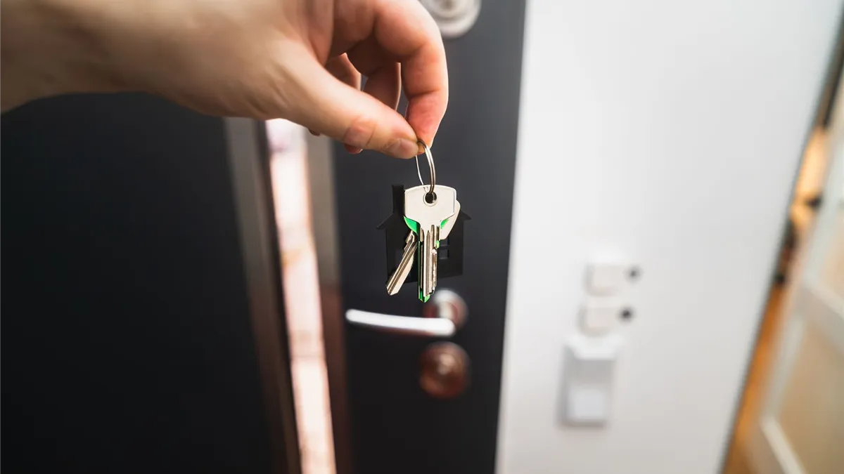 Hand holding the keys to a new home at the door after borrowing money for a move