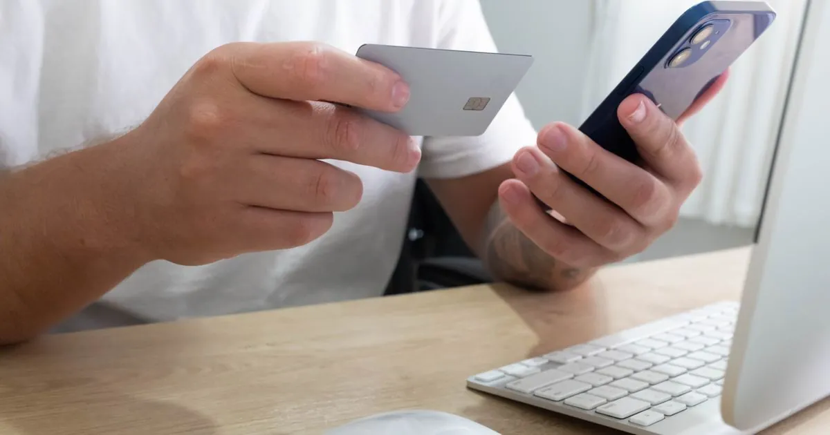 Applying for payday loans online in Canada using a card and phone at a desk