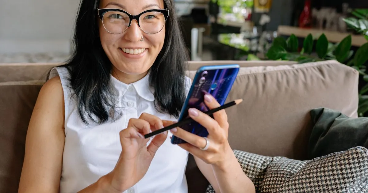 Smiling woman on her couch getting approved to borrow money instantly from her phone