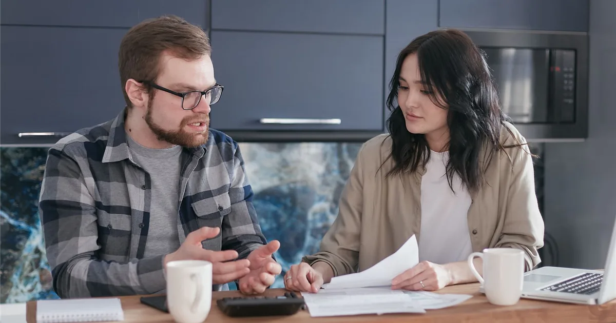 Couple at a kitchen table weighing the realistic ways to borrow money today in Canada