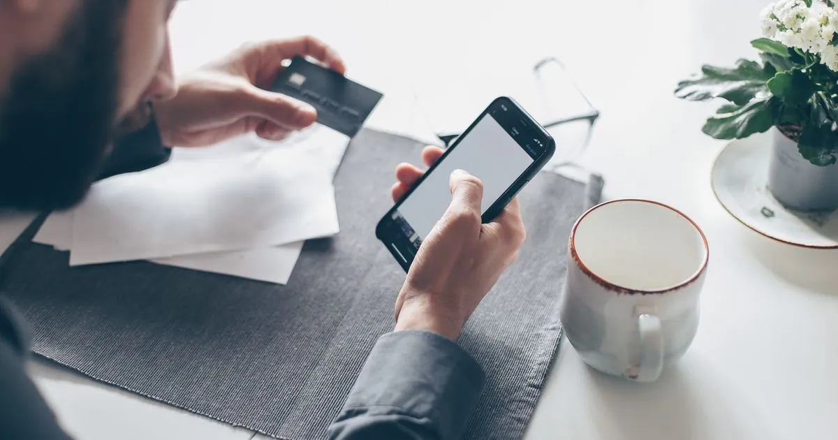 Checking a phone for instant e-transfer loans funding at a bright desk in Canada