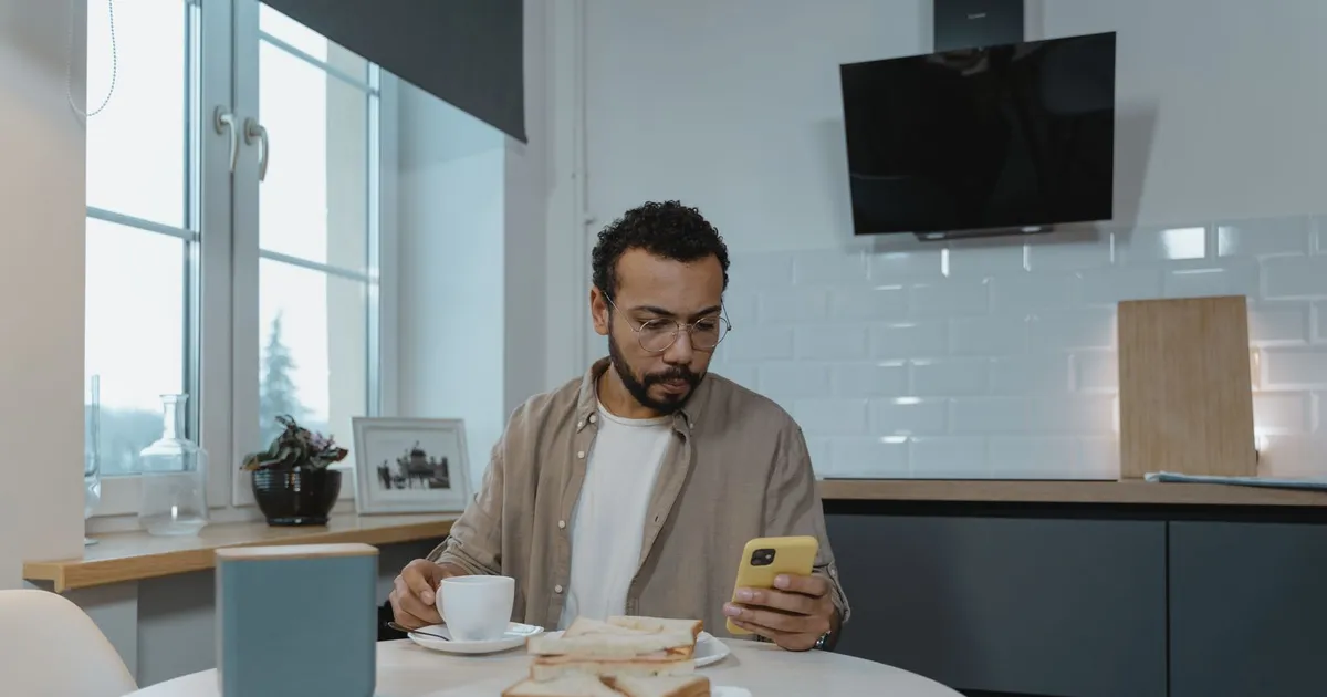 Man at his kitchen table applying on his phone for money now in Canada before the morning cutoff