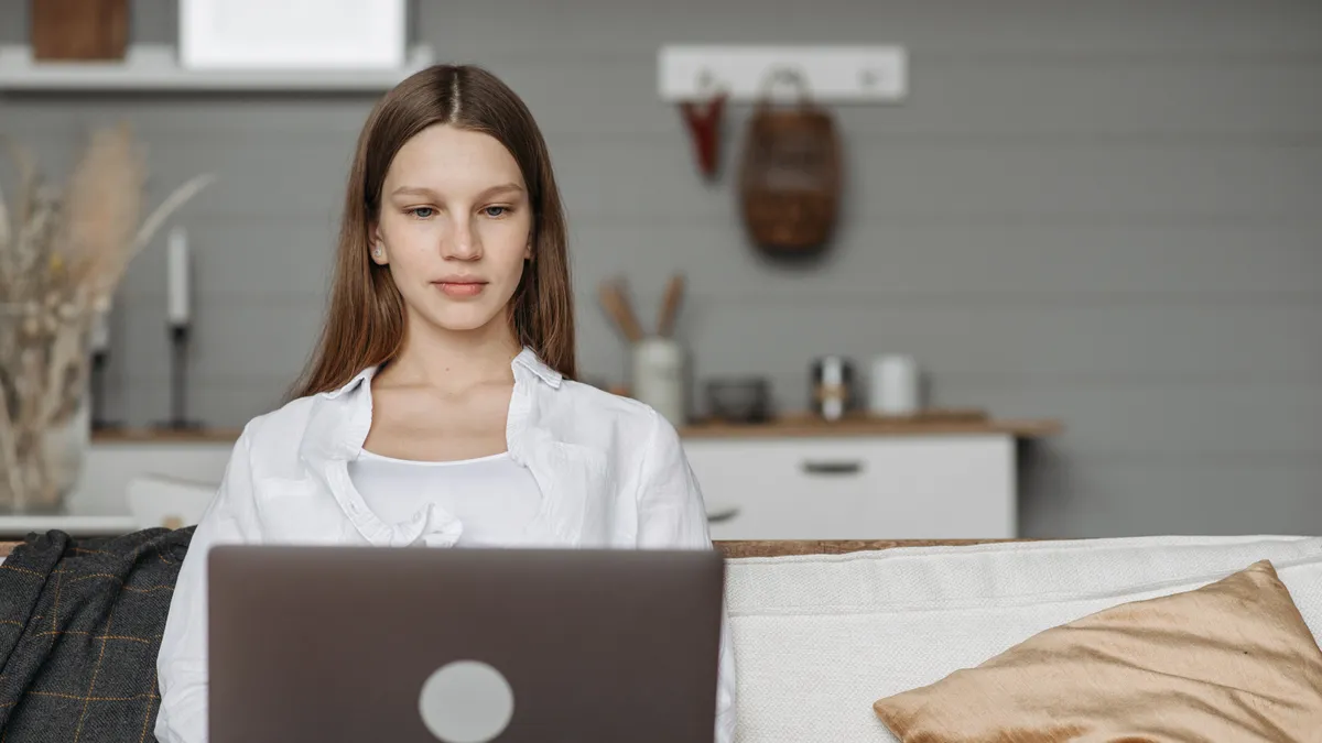 Woman on a couch filling in the online personal loans form on her laptop