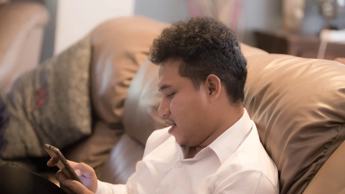 Young man on his couch checking the written offer on his online personal loans application