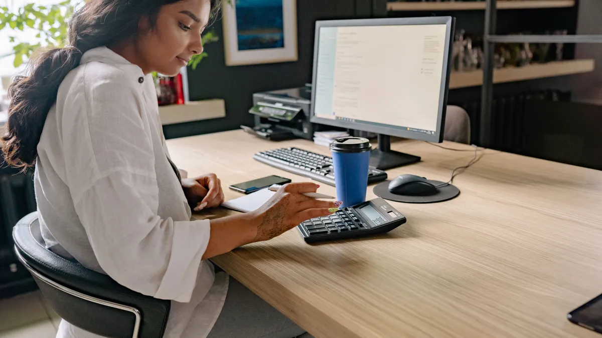 Woman at an office desk with a calculator working out the payment on online personal loans