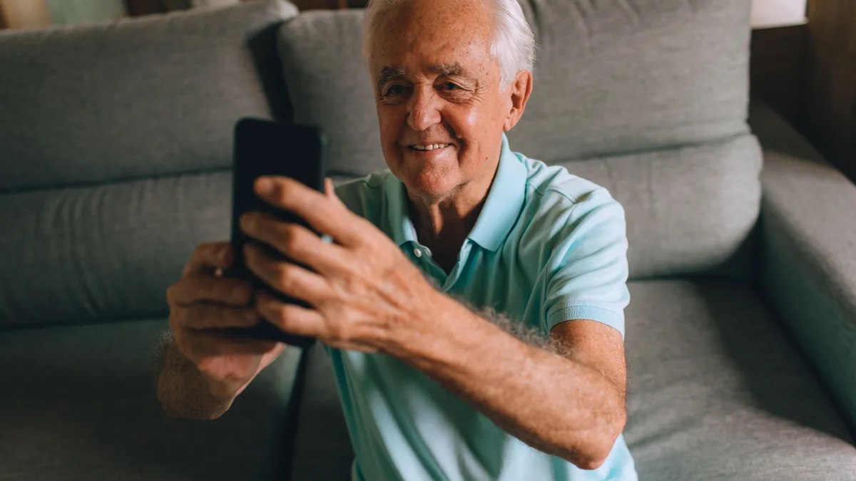 Older man on his sofa reading an online personal loans offer on his phone